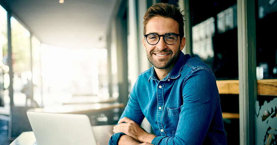 Un homme souriant devant un ordinateur portable